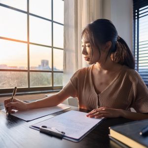 woman writing a book by a window in her den